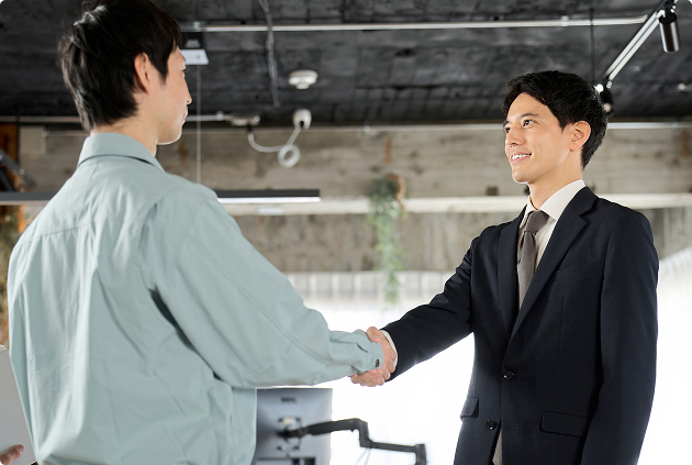 工場の責任者の方と株式会社アクアスのプロが握手している様子。